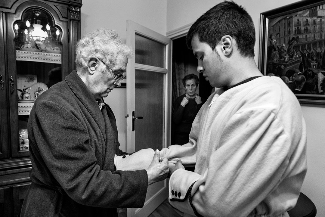 Un hombre mayor ayuda a un joven con una prenda ceremonial.